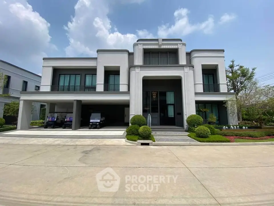 Luxurious modern mansion with elegant facade and manicured landscaping under a clear blue sky.