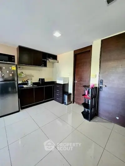 Modern kitchen with sleek cabinets and stainless steel fridge in a cozy apartment.