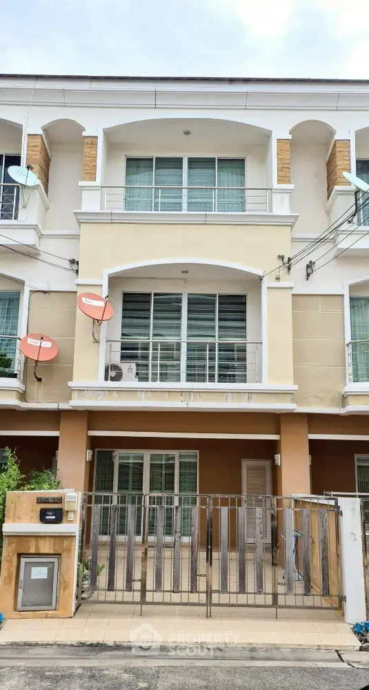 Modern three-story townhouse with balconies and gated entrance