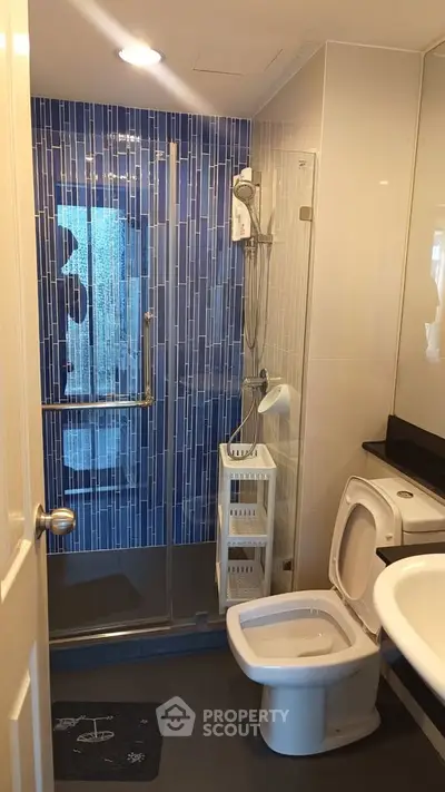 Modern bathroom with blue tiled shower and sleek fixtures