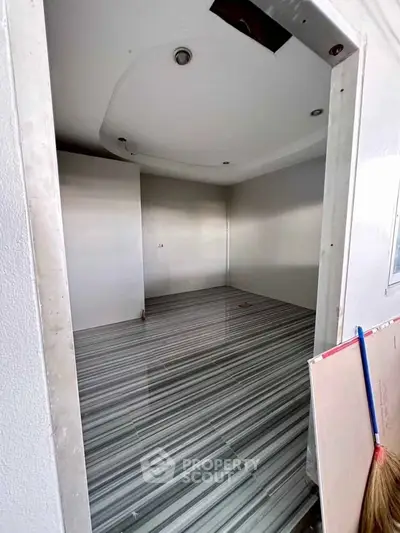Spacious empty room with modern striped flooring and recessed lighting, ideal for customization.