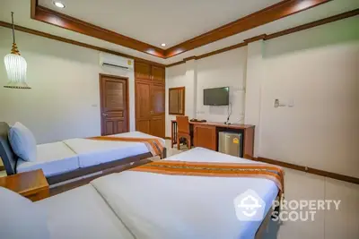 Inviting twin bedroom with elegant wood trim and cozy ambiance, featuring crisp white linens and modern amenities for a comfortable stay.