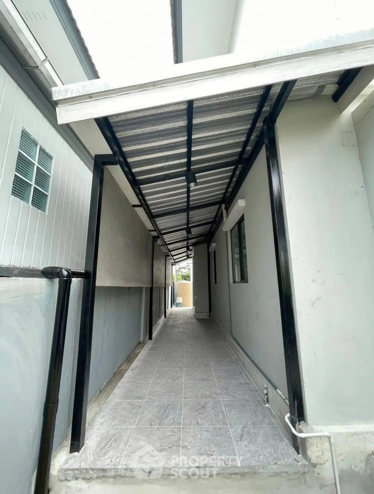 Modern covered walkway with sleek metal roofing and tiled flooring in residential property.