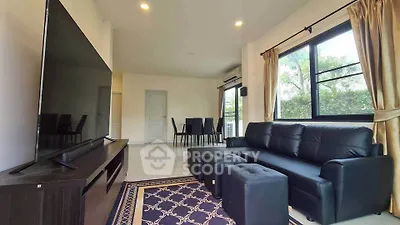 Spacious living room with modern black sofa and large TV, perfect for relaxation and entertainment.
