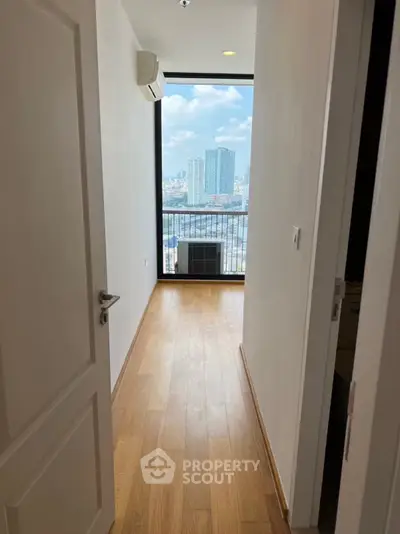 Bright room with wooden flooring and stunning city view from large window.