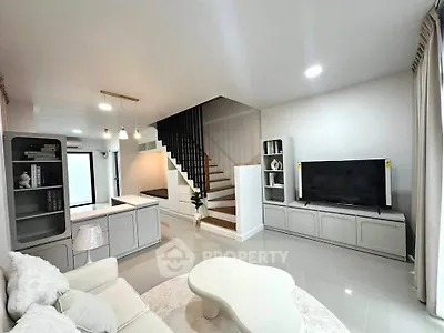 Modern living room with sleek design, featuring a staircase, TV unit, and stylish furniture.
