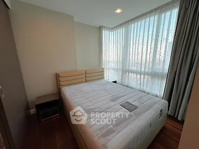 Cozy bedroom with large windows and modern furnishings, offering ample natural light.