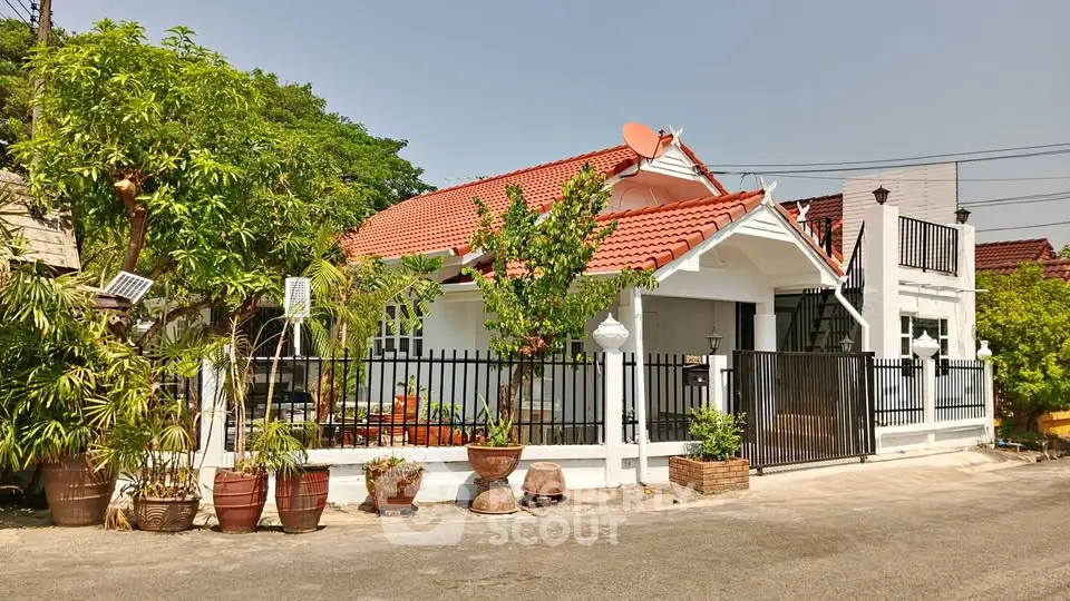 Charming single-story house with red tile roof and lush garden in a serene neighborhood.