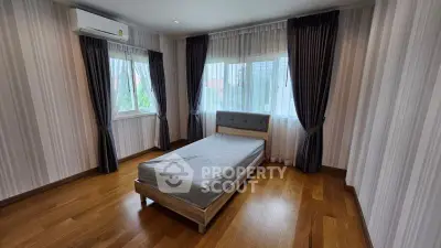 Spacious bedroom with wooden flooring and large windows for natural light.