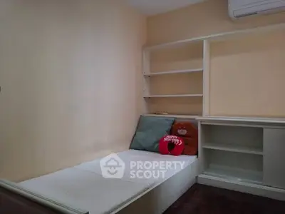 Cozy small bedroom with built-in shelves and air conditioning, perfect for compact living.