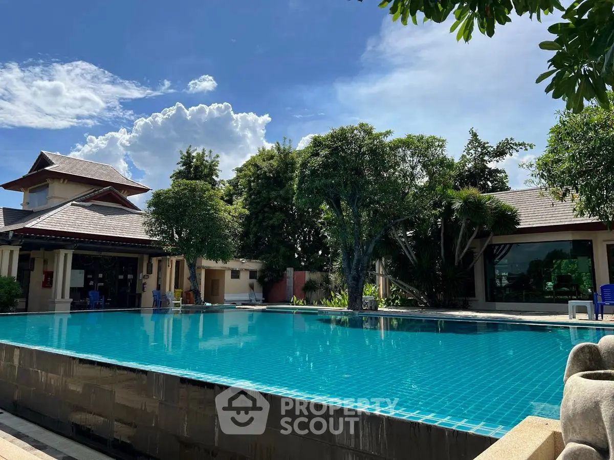Luxurious outdoor pool area with lush greenery and clear blue sky, perfect for relaxation and leisure.
