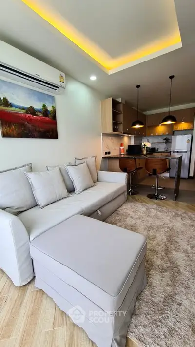 Modern living room with open kitchen, featuring cozy sofa and stylish bar stools.