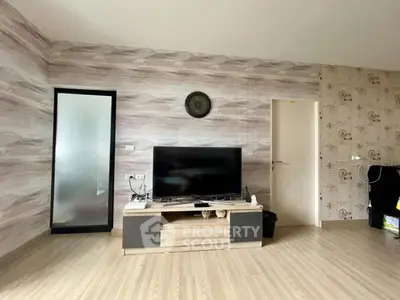 Modern living room with stylish decor and wooden flooring, featuring a sleek TV stand and wall clock.