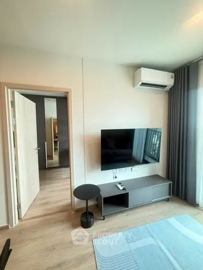 Modern living room with sleek TV setup and air conditioning, featuring stylish decor and natural light.