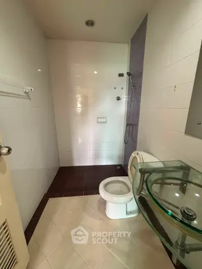 Modern bathroom with glass sink and shower area in contemporary apartment.