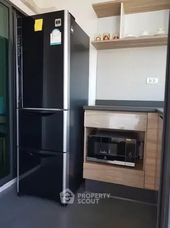 Modern kitchen corner with sleek black fridge and built-in microwave