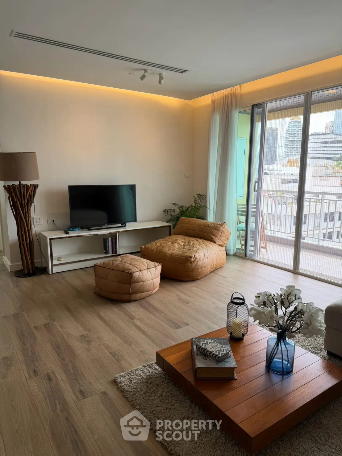 Spacious modern living room with stylish decor and large windows offering city views.