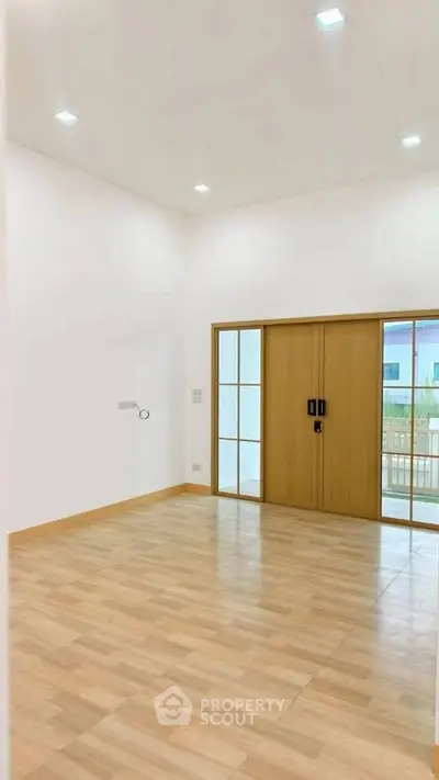 Spacious empty room with wooden sliding doors and bright lighting, ideal for customization.