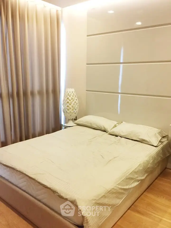 Modern bedroom with elegant decor and soft lighting, featuring a comfortable bed and stylish lamp.