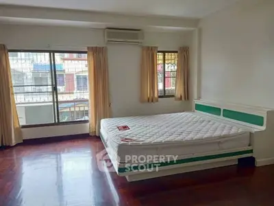 Spacious bedroom with large windows and hardwood floors in a well-lit apartment.