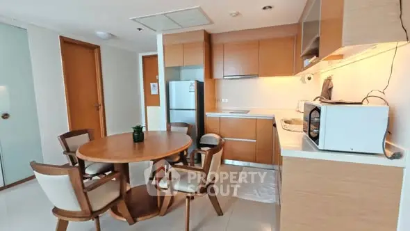 Modern kitchen with dining area featuring wooden cabinets and round table.