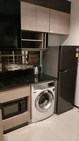 Modern kitchen with sleek appliances including washing machine and fridge, ideal for urban living.