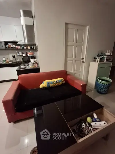 Cozy living room with modern kitchen, red sofa, and sleek black coffee table in a stylish apartment.