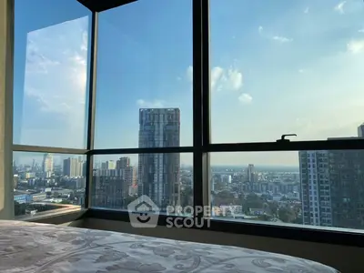 Stunning cityscape view from a high-rise apartment window with clear blue skies.