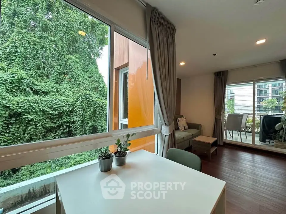 Charming living room with large windows and balcony view, perfect for relaxation and natural light.