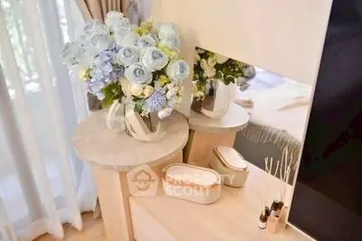 Elegant bedroom corner with floral arrangement and decorative items on a wooden dresser.