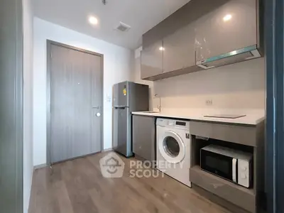 Modern kitchen with sleek cabinets, washing machine, and microwave in compact layout.