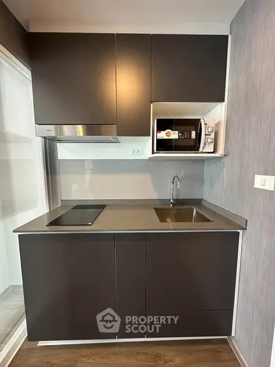 Modern compact kitchen with sleek cabinetry and built-in microwave
