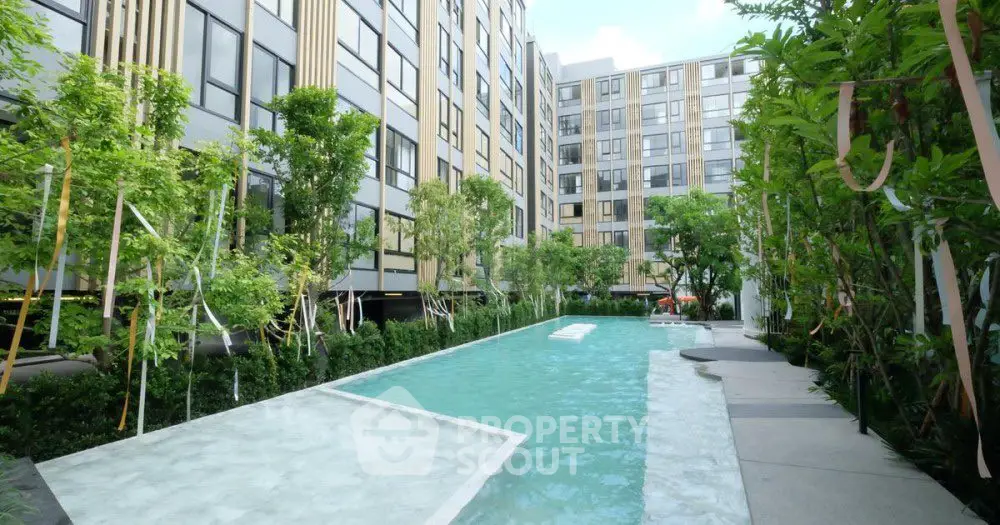 Modern apartment complex with lush greenery and inviting swimming pool