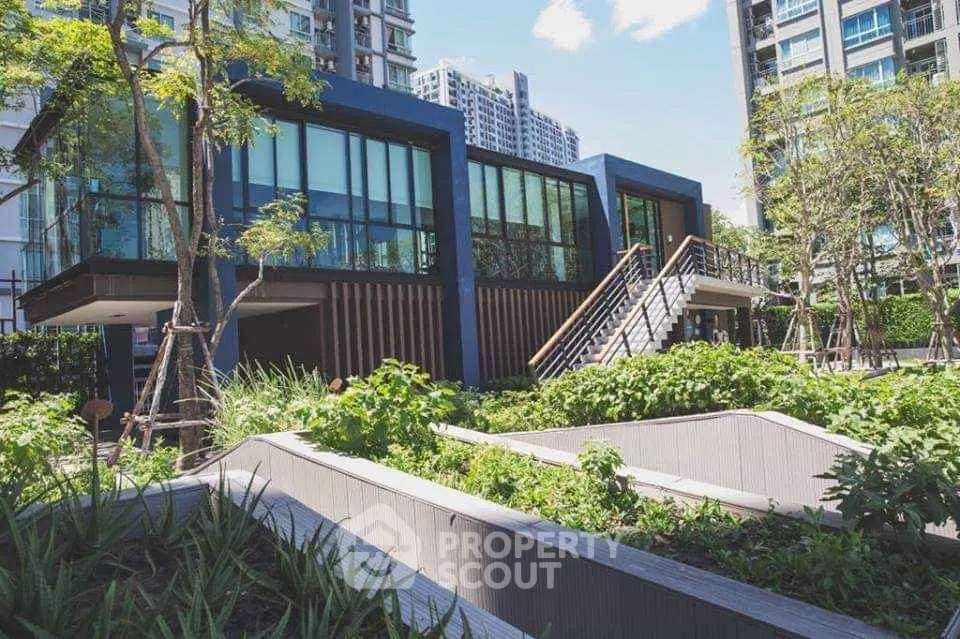Modern building exterior with lush garden and sleek architecture in urban setting.