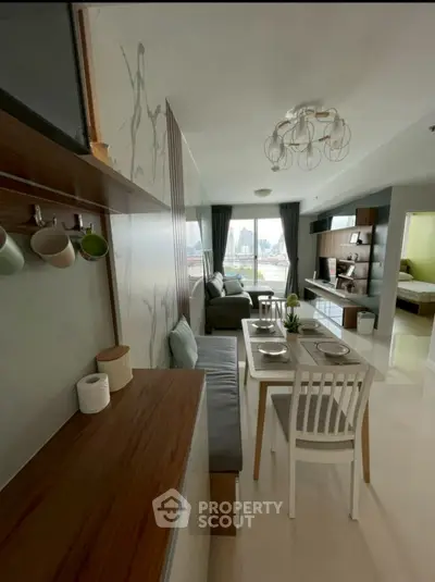 Modern open-plan living room with dining area and city view, featuring stylish decor and natural light.