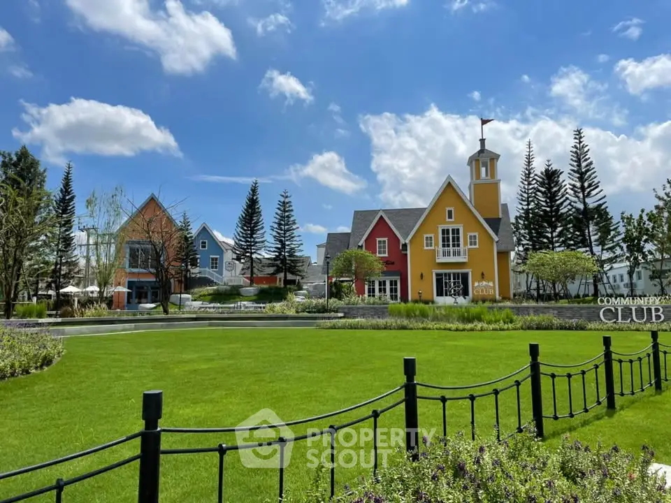 Charming community club with colorful houses and lush green lawn under blue sky.