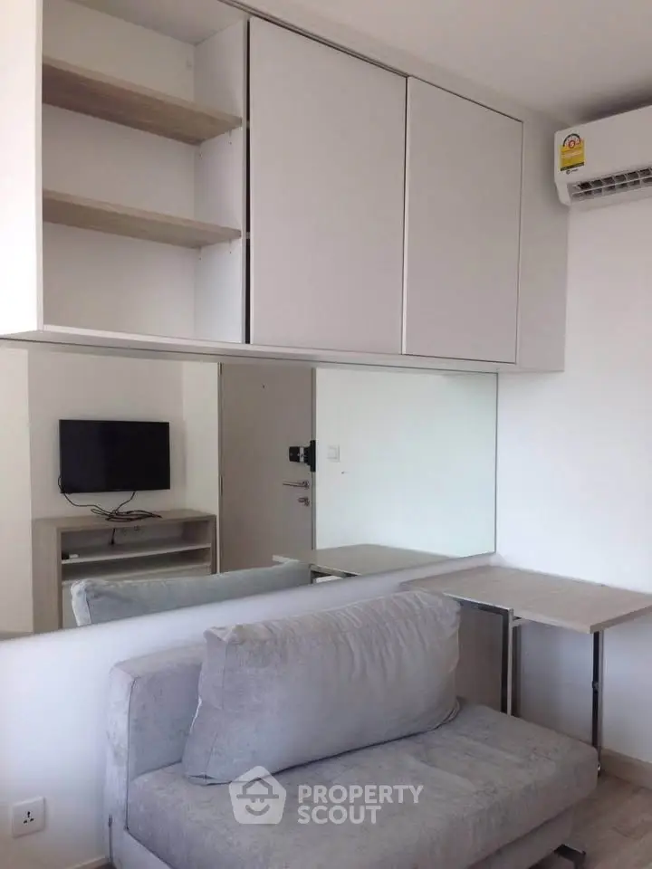 Modern living room with sleek furniture and wall-mounted TV in a compact apartment.