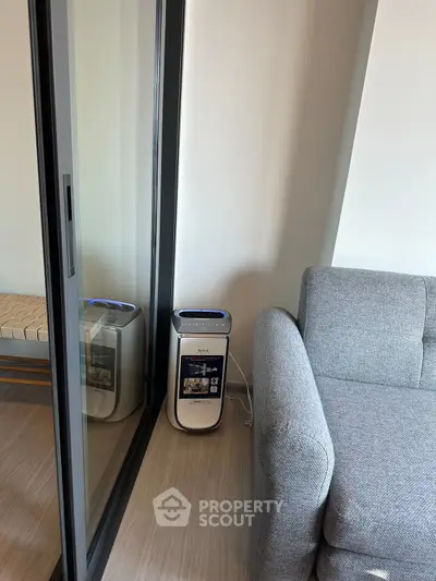 Modern living room with sleek air purifier and stylish gray sofa near glass sliding door.