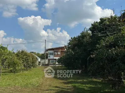Charming countryside house with lush greenery and clear blue sky, perfect for serene living.