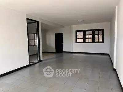 Spacious unfurnished room with tiled flooring and large windows, ideal for customization.