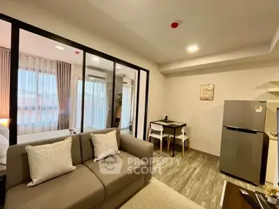 Modern living room with glass partition, cozy sofa, and dining area in stylish apartment.