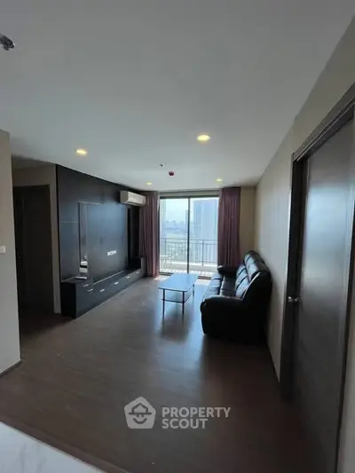 Spacious living room with modern decor and city view balcony in a high-rise apartment.