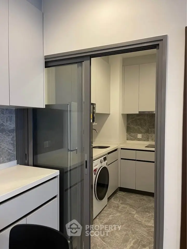 Modern kitchen with sleek cabinetry and integrated washing machine in compact layout.