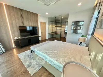Modern bedroom with sleek design, featuring a large bed, wall-mounted TV, and stylish wooden accents.