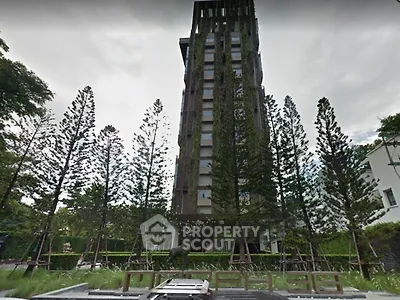 Modern high-rise building with lush greenery and tall trees in the foreground.