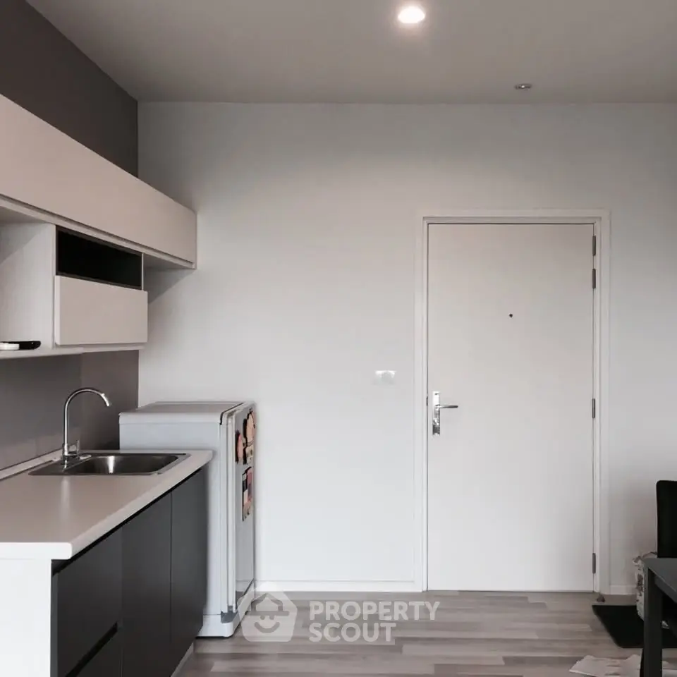 Modern kitchen with sleek cabinetry and compact fridge in a stylish apartment.