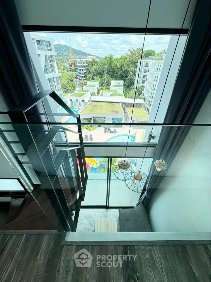 Stunning view from modern apartment with floor-to-ceiling windows overlooking pool and lush greenery.