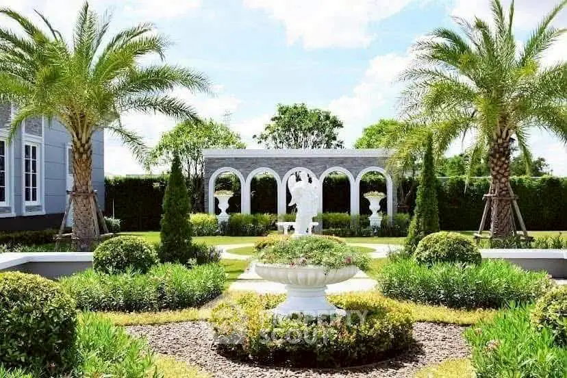 Luxurious garden with elegant statues and lush greenery in a high-end property.