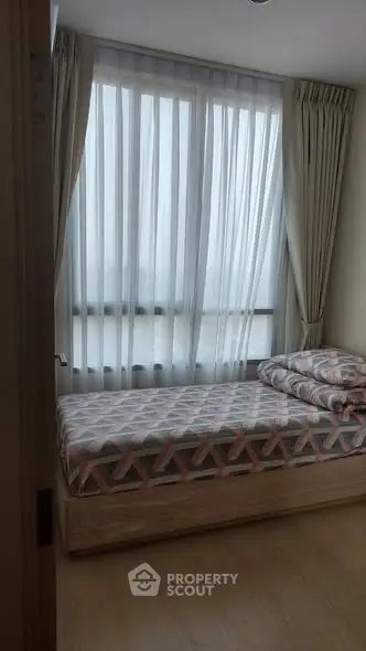 Cozy bedroom with large window and stylish bedding in modern apartment.