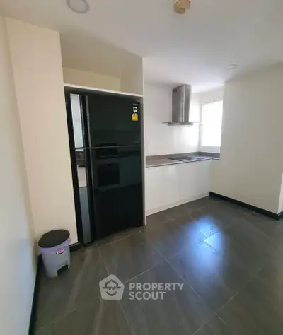 Modern kitchen with sleek black fridge and stainless steel range hood in a minimalist design.